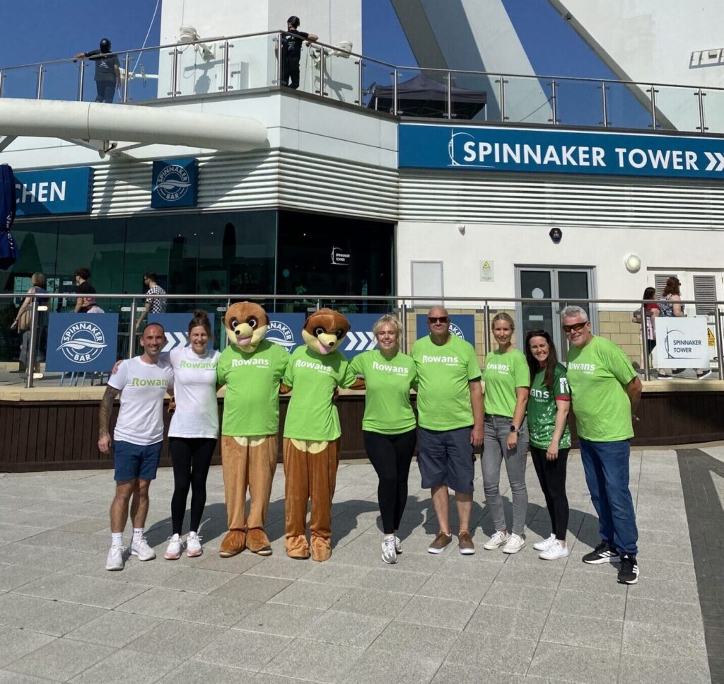 line of people and mascots for rowans hospice at bottom of spinnaker tower on sunny day after abseiling
