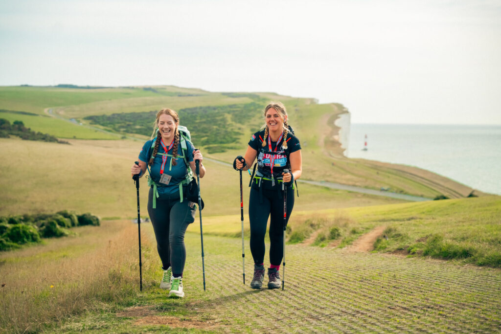 Two women walking up a cliff with walking gear