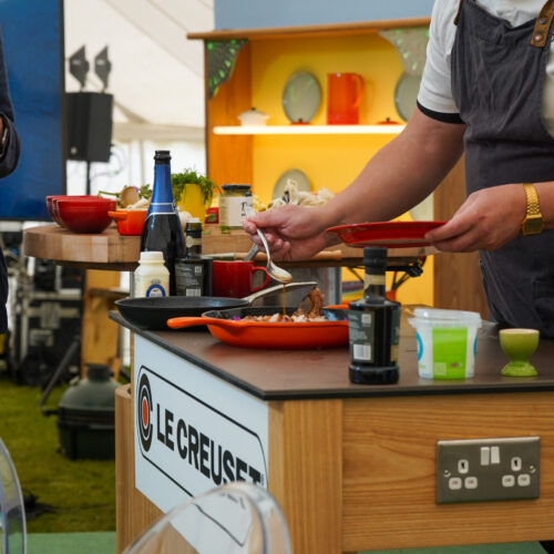 Man in chef uniform cooking in a branded "Le Creuset" Kitchen