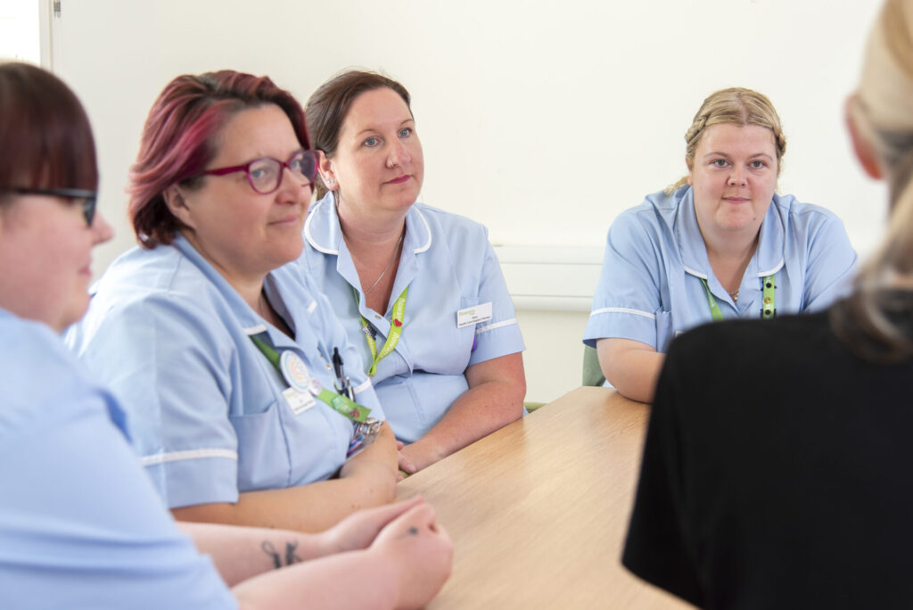 Nurses sitting at a desk in a group meeting