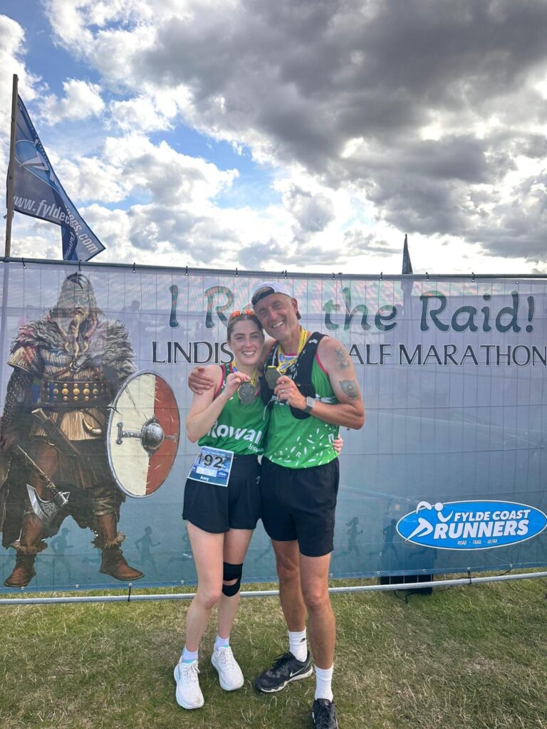 Daughter and father holding medals and smiling after completing a half marathon