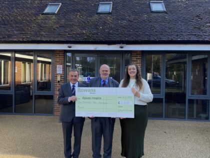 two men in formalwear holding a cheque presentation with a lady