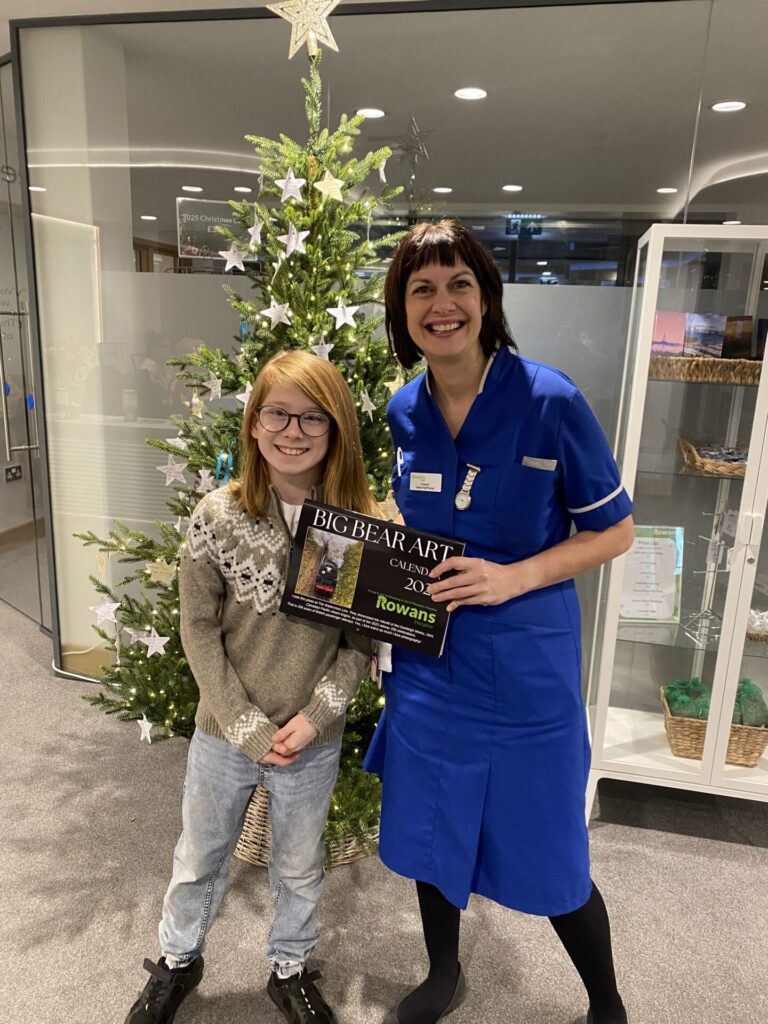 nurse and small boy holding a calendar infront of a christmas tree