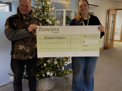 man and woman holding cheque in front of christmas tree
