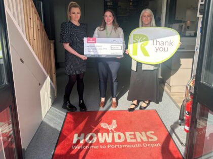 three ladies stood in a doorway holding thank you signs and a cheque