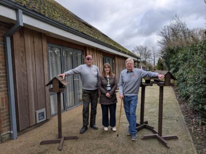 men stood next to wooden bird feeders with a woman