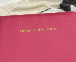 pink booklet photographed from top view reading helen b this is me