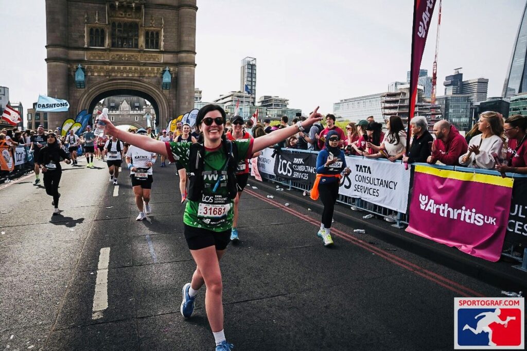 woman in green tshirt running and celebrating with arms up.