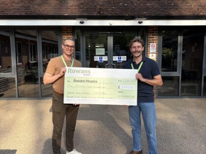 photo of two men outside rowans hospice building holding a cheque and smiling at the camera after raising money for the charity
