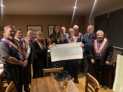 a group of people facing the cameraa holding a cheque presentation in support of rowans hospice