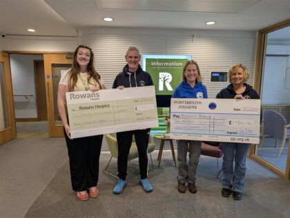four people holding two cheques with money raised for rowans hospice in a reception