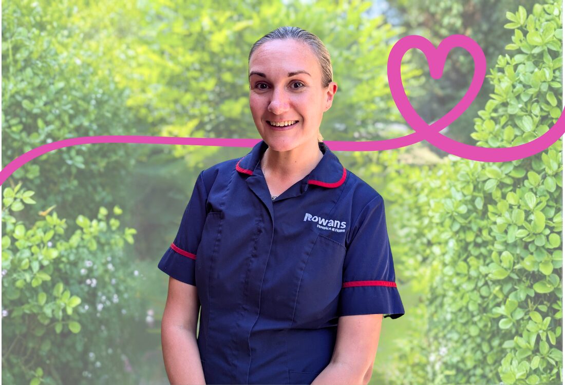Woman in dark blue nurse uniform smiling to camera.