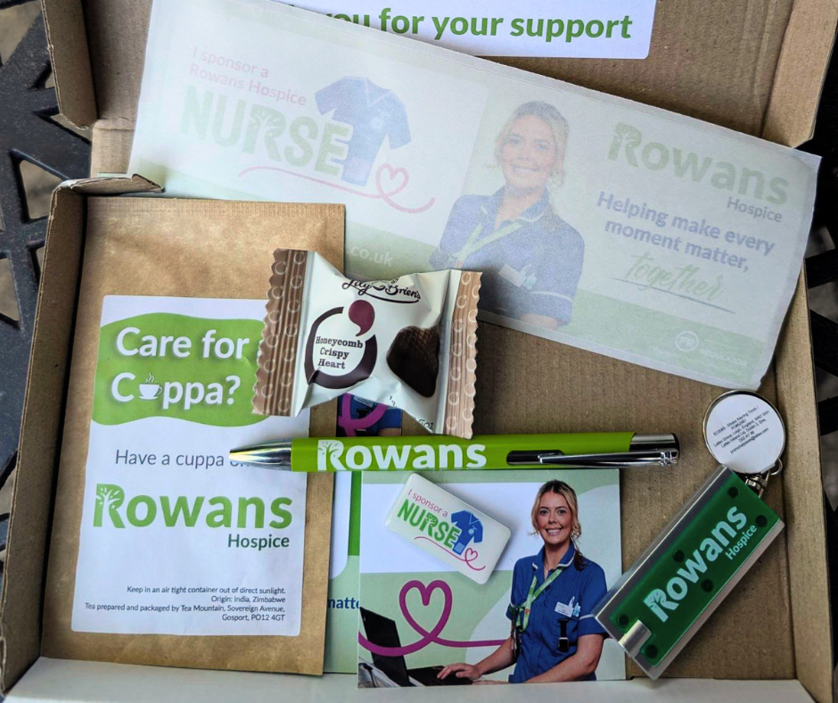 Box with small chocolate, individually wrapped tea bag, green pen with"Rowans Hospice" written on it, "Sponsor a nurse" rectangle pin badge, small torch keyring and car sticker